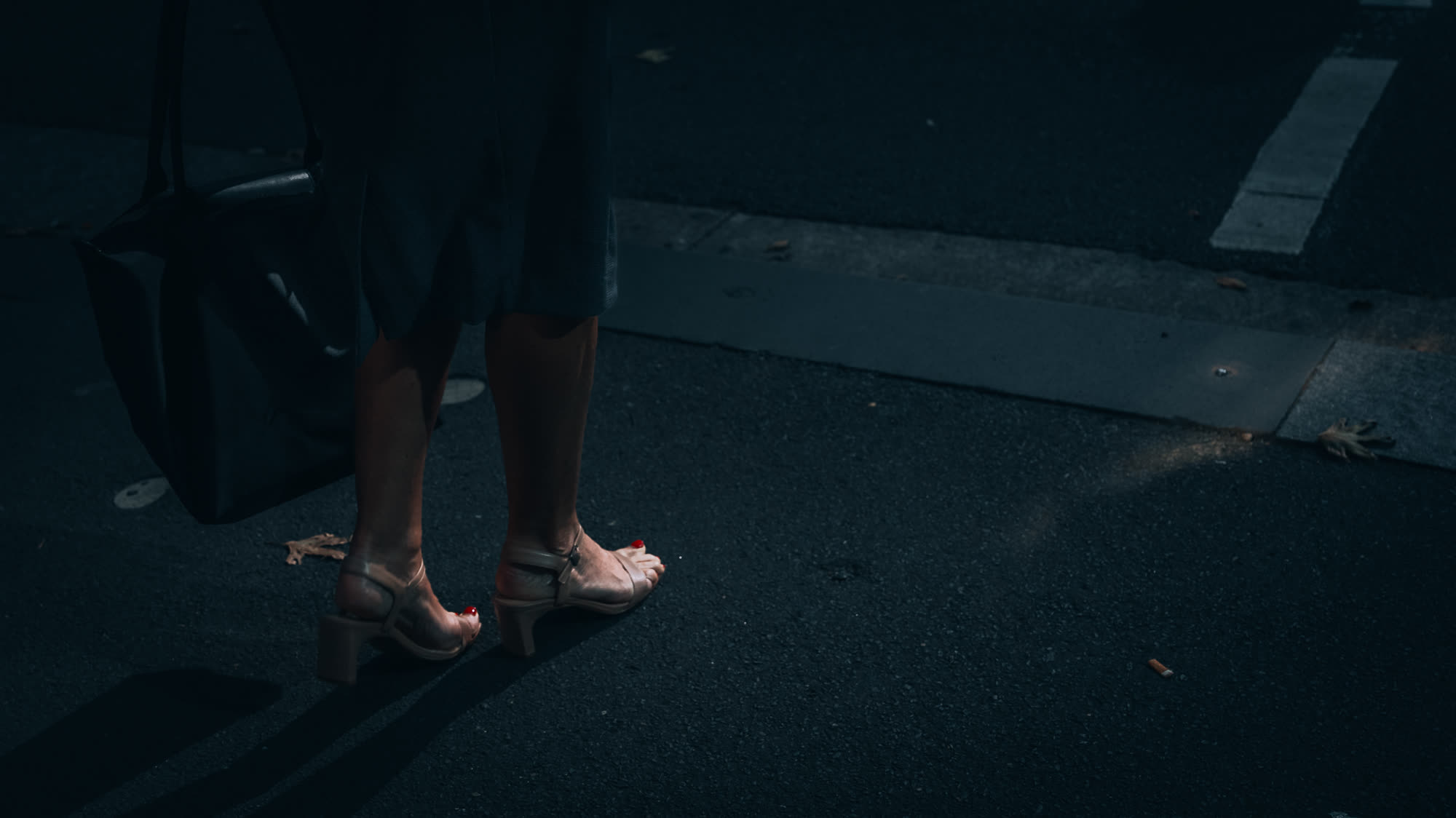 Heels and a tote bag on the pavement, shot from behind